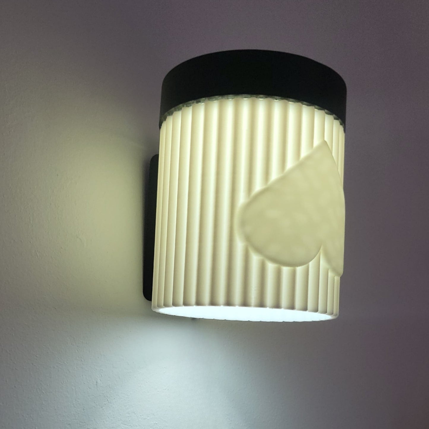 Wall-mounted light fixture with ribbed design and heart shape on a gray background