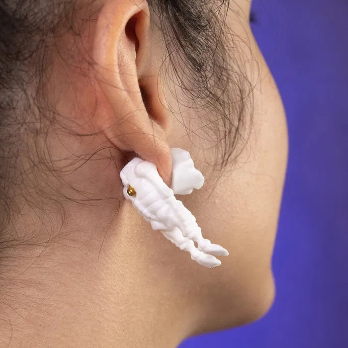 A pair of skeleton earrings hanging from a display stand, emphasizing their handcrafted look and unique shape that adds character to any alternative outfit.