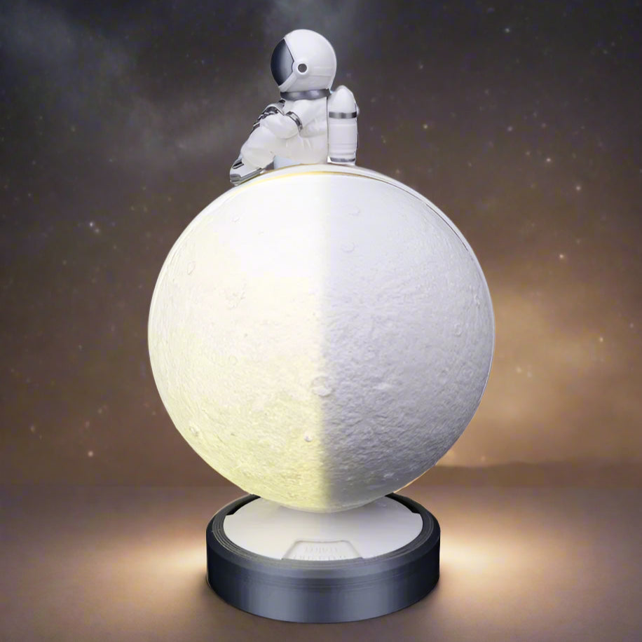 Top-down view showing the astronaut figurine sitting on the moon lamp"
Shot from above, this image highlights the small astronaut figure sitting atop the moon lamp. The intricate details of the figurine’s helmet and suit contrast with the moon’s cratered surface.