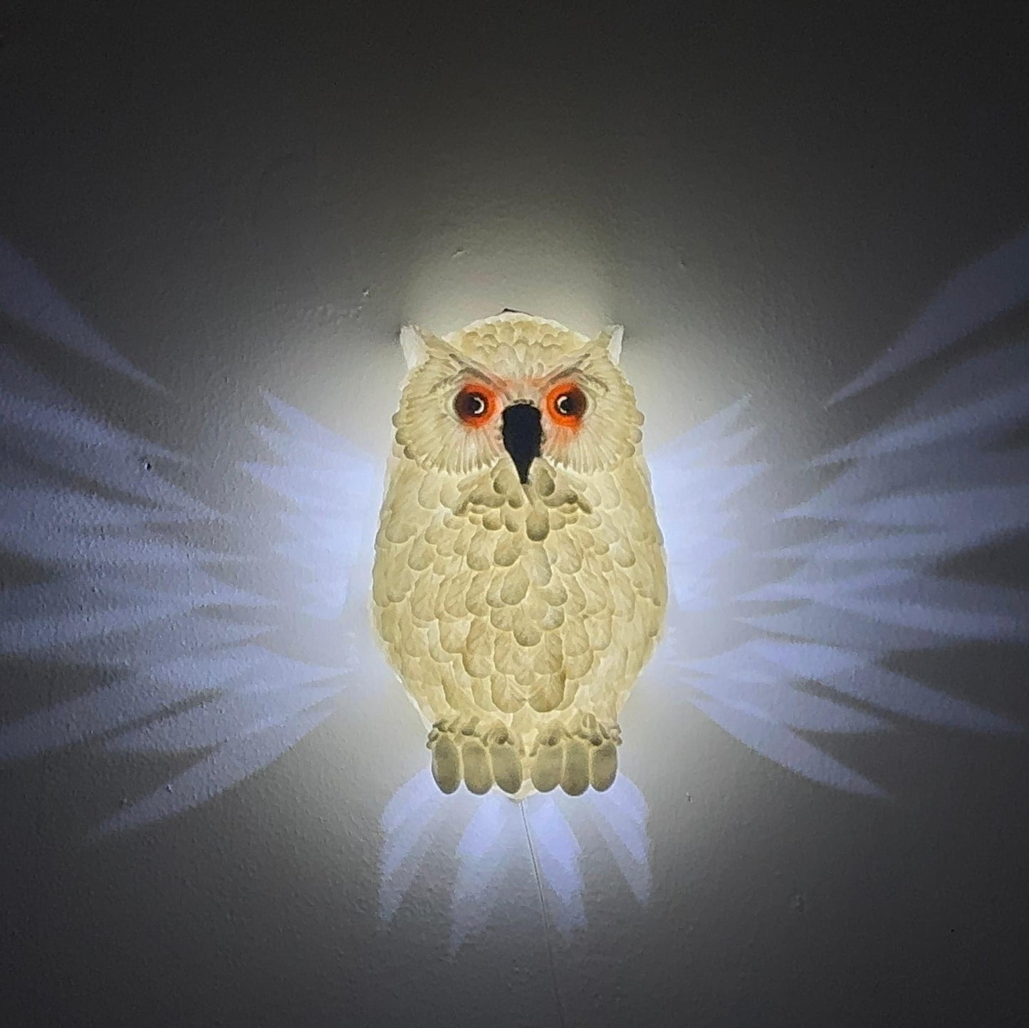 Side view of the Hedwig the Owl Night Lamp mounted on the wall, with light gently spreading from the owl's wings