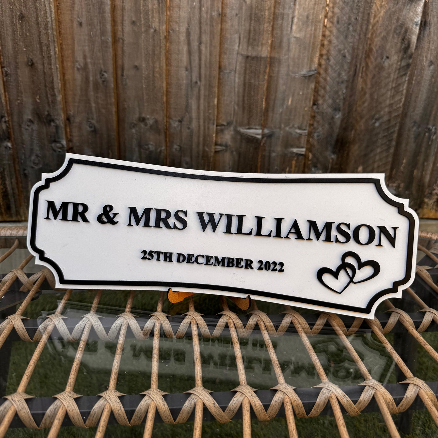Personalized sign for Mr & Mrs Williamson with wedding date against a wooden fence background