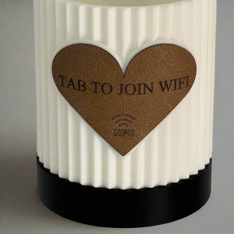 White textured candle with a brown heart-shaped label on a gray background