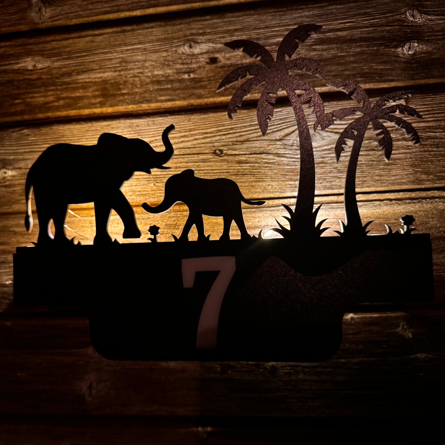 Indoor black wooden decorative sign with a matte texture, displayed in a cozy living room setting, mounted on the wall with one of the available design templates.