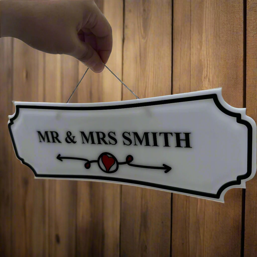 Decorative sign with 'MR & MRS SMITH' text held in front of a window.