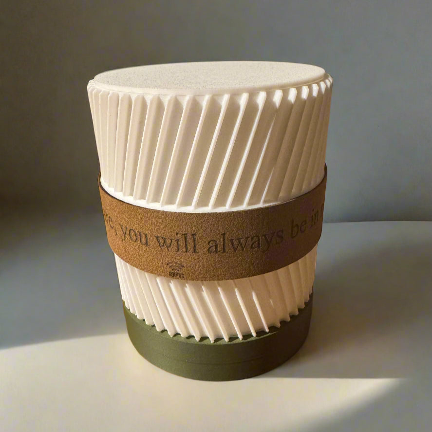 White textured candle with a brown band and text on a gray background