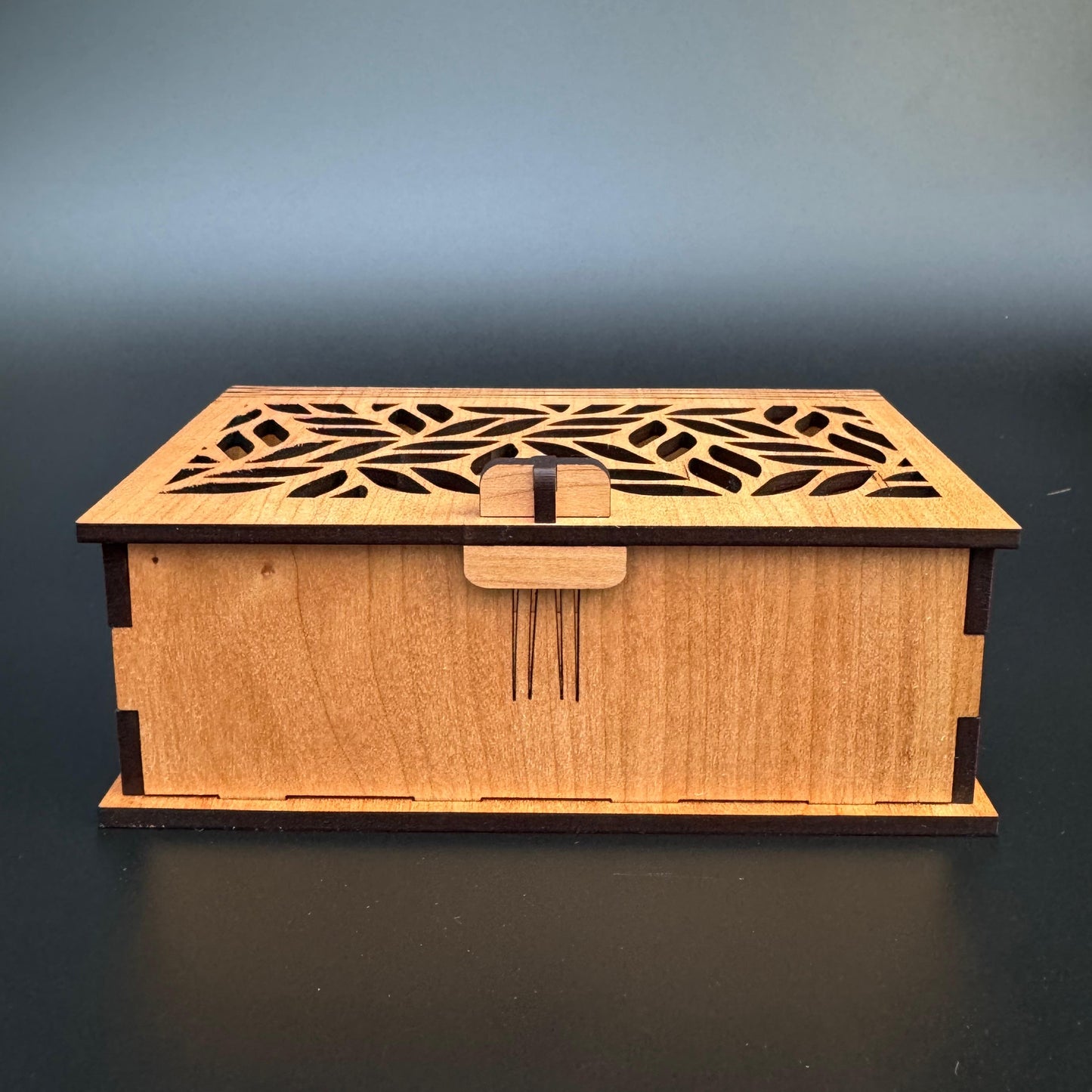 Wooden box with laser-cut design on a dark background