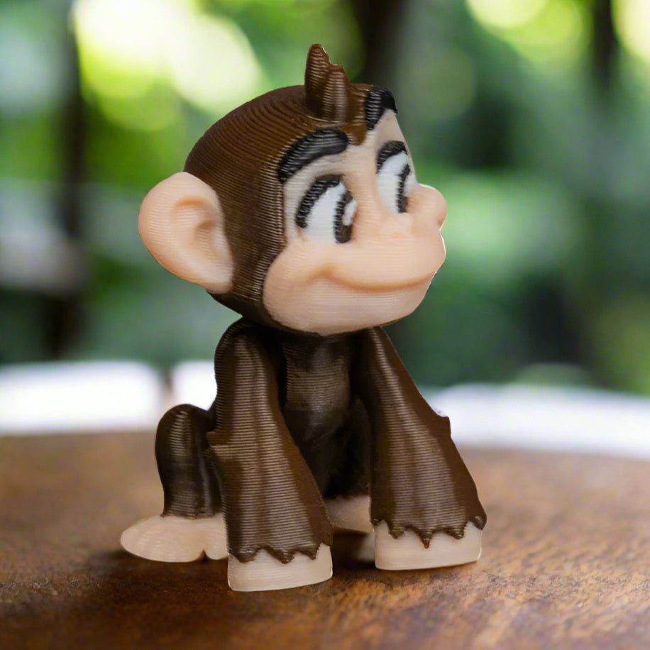 A hand gently holding the monkey keychain to show its small size and light weight; the details of the face, ears, and curved tail are clearly visible, emphasizing the fine craftsmanship.