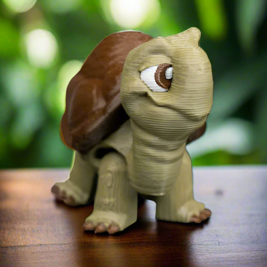 Turtle keychain sitting on a wooden surface, showcasing its shell detail and rounded shape, perfect as a riverside-themed accessory or gift.