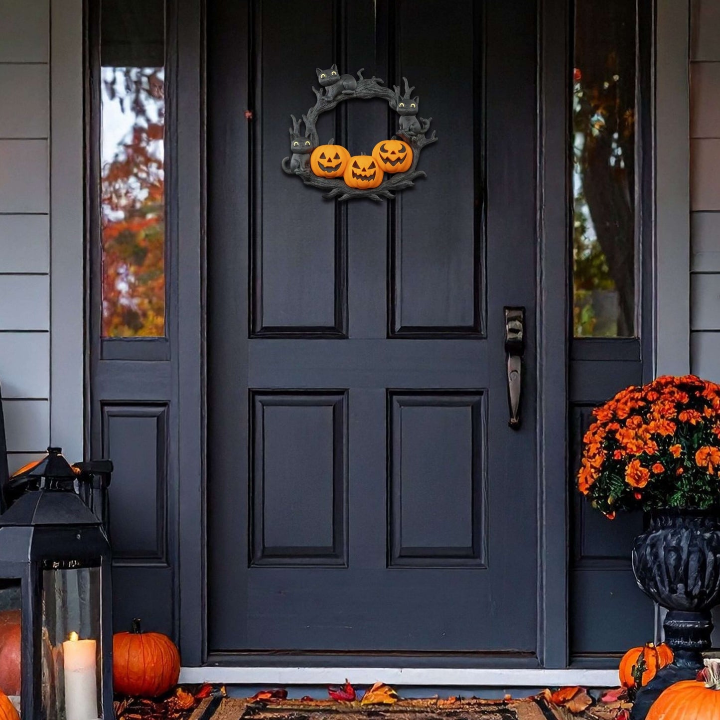 Decorative Halloween wreath on a black door with pumpkins and leaves on the ground.