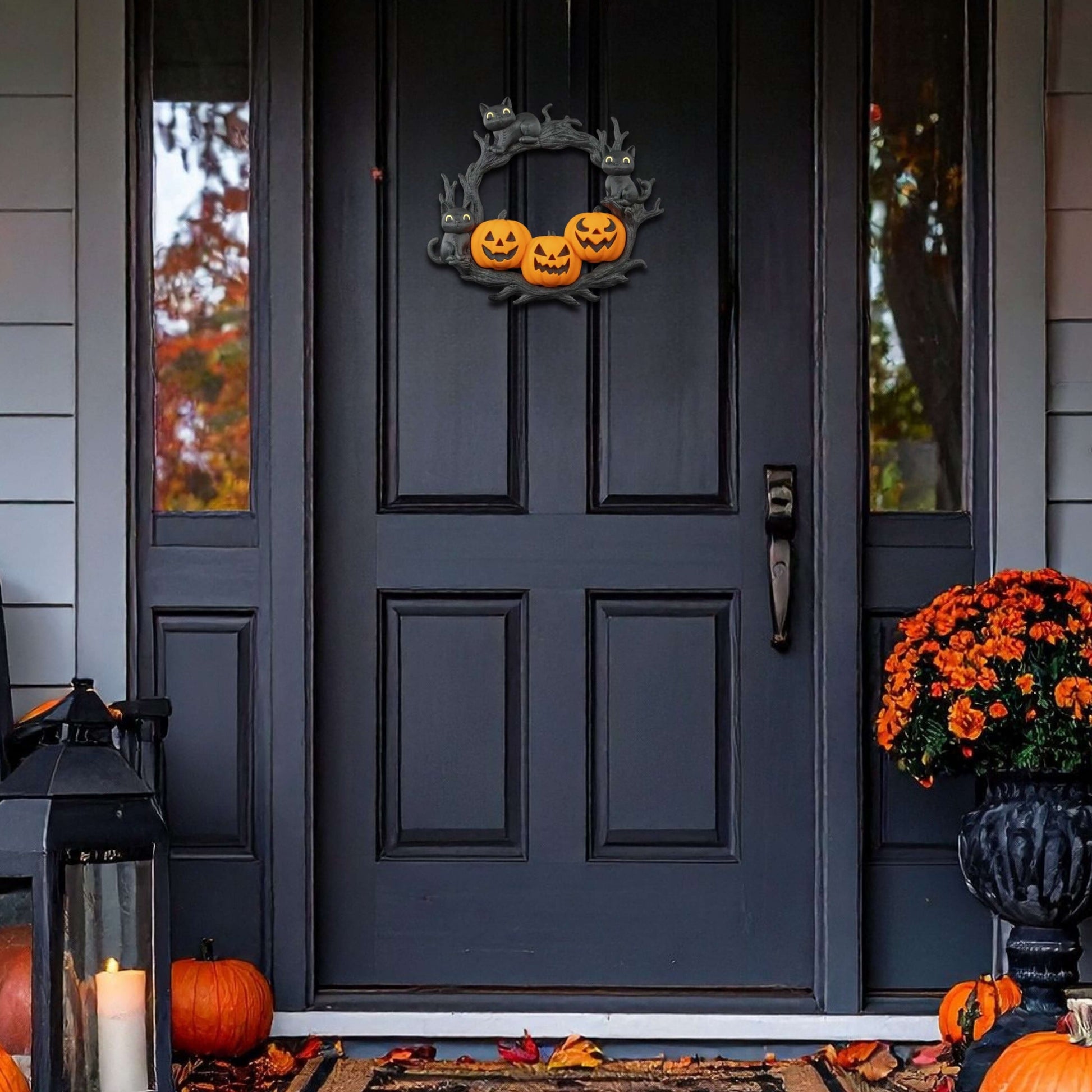 Decorative Halloween wreath on a black door with pumpkins and leaves on the ground.