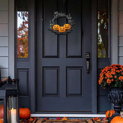 Decorative Halloween wreath on a black door with pumpkins and leaves on the ground.