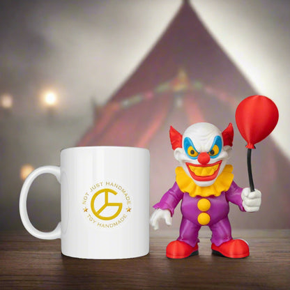 White mug with yellow logo and clown figurine holding a red balloon against a blurred circus tent background