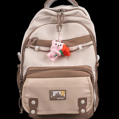 Beige backpack with a teddy bear keychain on a black background