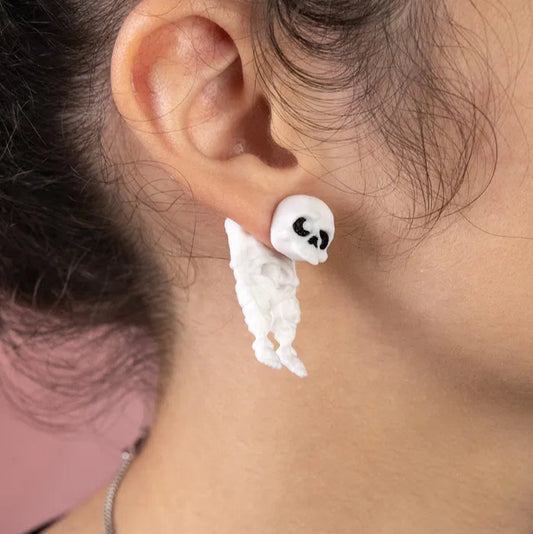 Skeleton-shaped dangle earrings placed on a neutral background, showcasing their detailed design and lightweight construction for everyday spooky style.