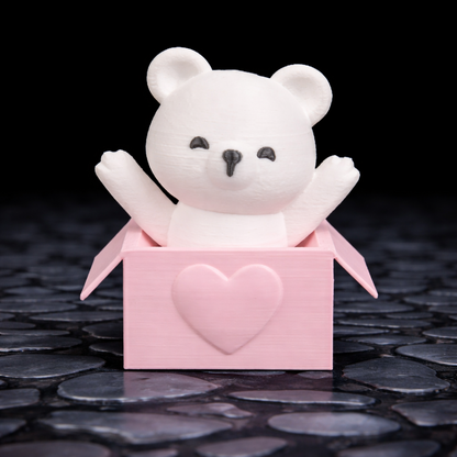 White teddy bear in a pink box with a heart on a dark surface