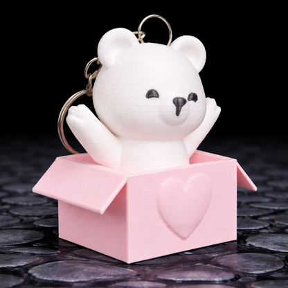 White bear keychain in a pink box on a dark stone surface
