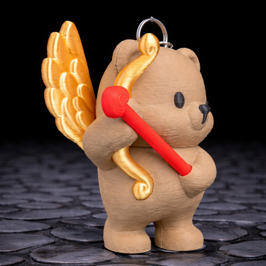 Teddy bear keychain with wings and a bow on a dark stone surface