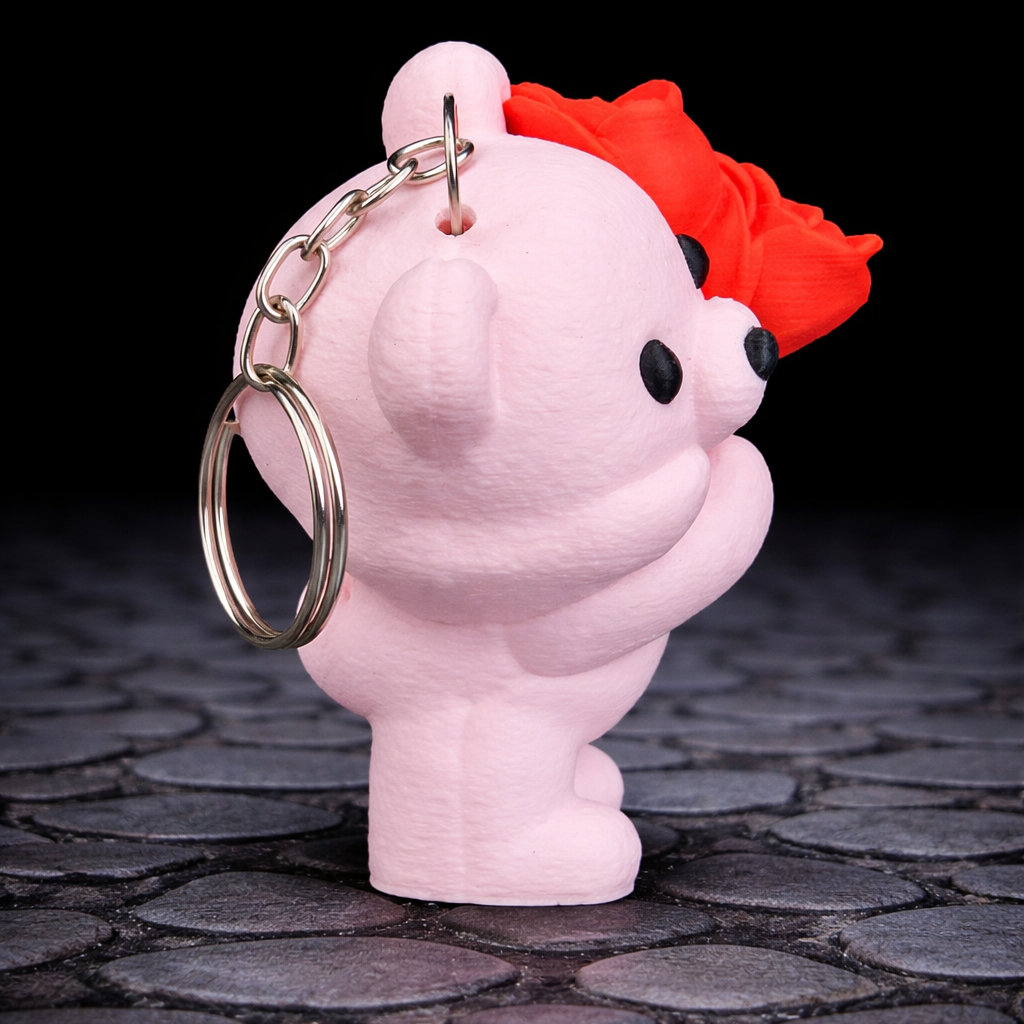 Pink keychain with a red hair accessory on a dark stone surface
