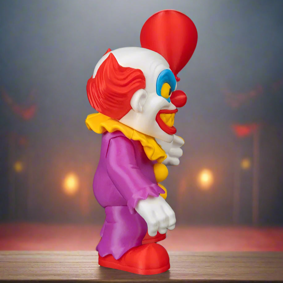 Colorful clown figurine with red balloon on a black background
