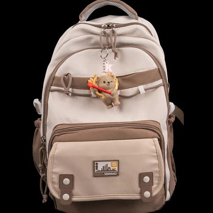 Beige backpack with a teddy bear charm on a white background