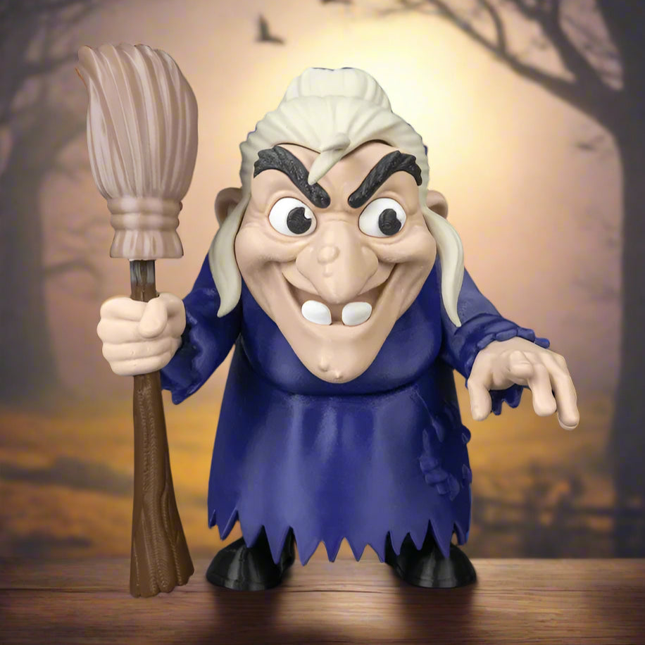 Toy figure of an elderly witch holding a broom against a black background