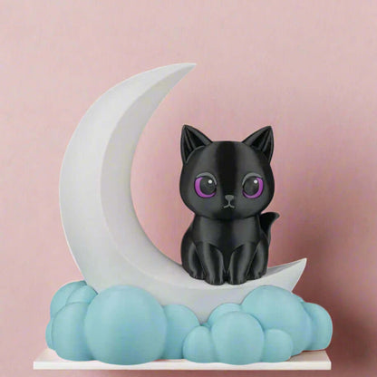 Black cat figurine on a white crescent moon with blue clouds against a pink background