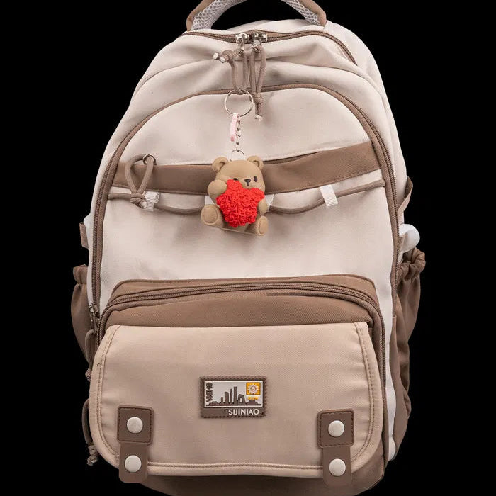 Beige and brown backpack with a teddy bear keychain on a black background