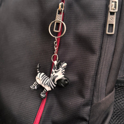 Zebra keychain hanging from a backpack zipper, showing the high-detail 3D-printed finish and playful safari theme.
