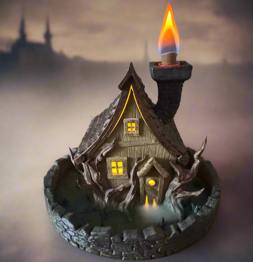 Decorative candle holder shaped like a haunted house with a lit candle on a dark background.