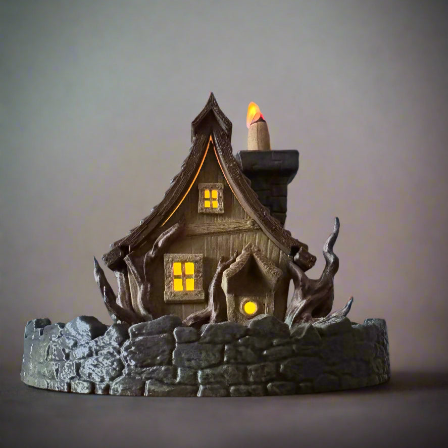 Decorative haunted house with glowing windows and a candle on a gray background