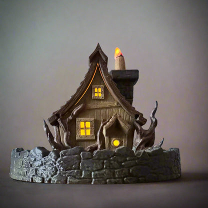 Decorative haunted house with glowing windows and a candle on a gray background