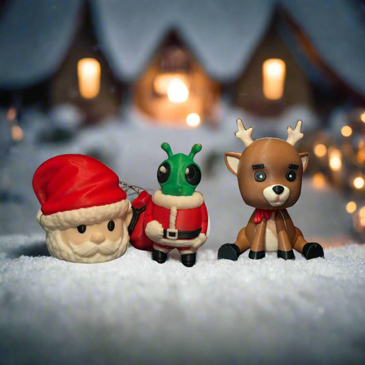 Three Christmas-themed figurines on a snowy surface with a blurred festive background.