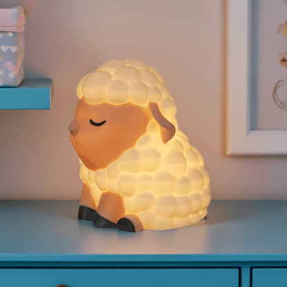 Sheep-shaped night light on a blue surface with a soft background