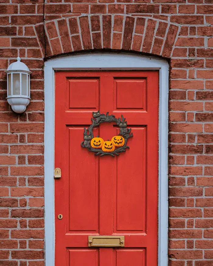 Red door with Halloween wreath on a brick wall