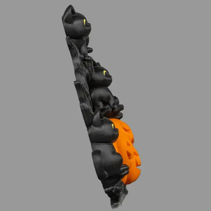 Decorative item with black cat figures and an orange paw print on a gray background