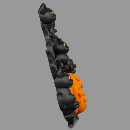 Decorative item with black cat figures and an orange paw print on a gray background