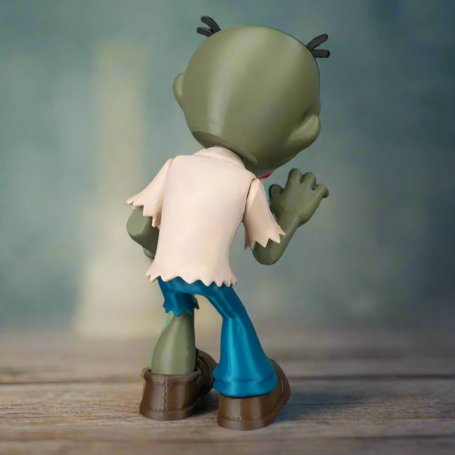 Toy figure of a character with green skin, white shirt, blue pants, and brown shoes on a wooden surface.