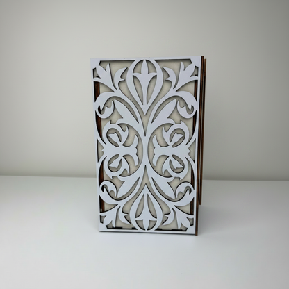 Decorative wooden frame with intricate white cut-out design on a plain background